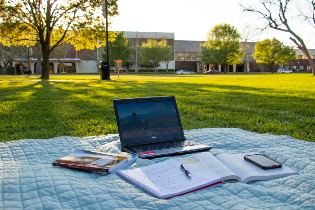 Laptop sitting on picnic blanket on campus