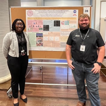 Two researchers standing beside a scientific poster titled 