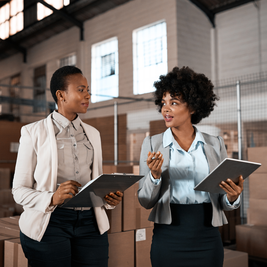 Two women having a discussion in a warehouse.