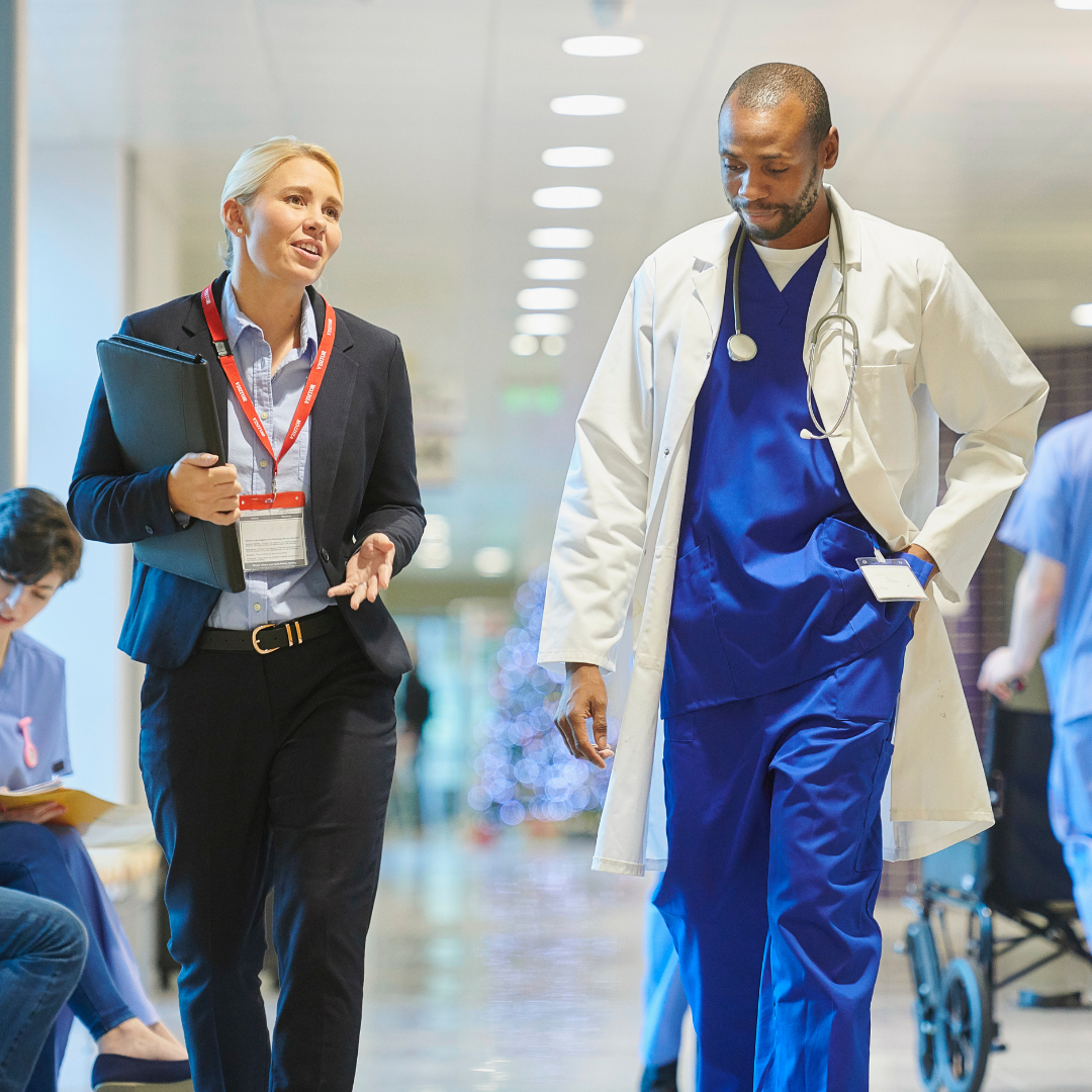 Healthcare administrator talking with a doctor in a hospital.