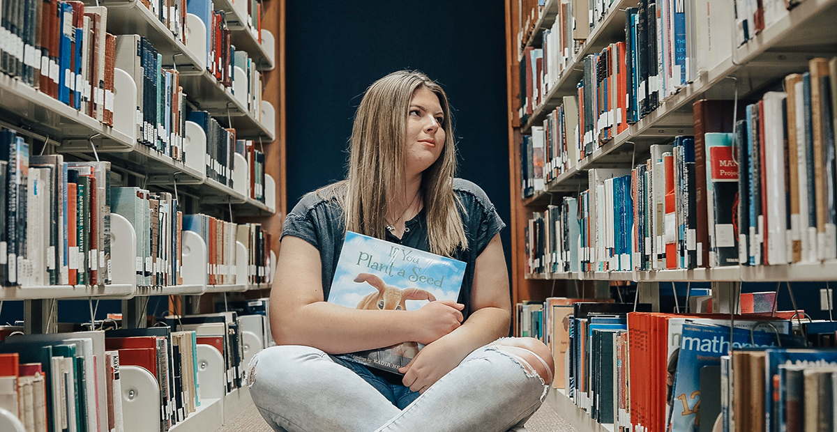girl sitting on the floor in the library with a book