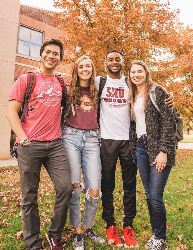 Four students standing on Campus smiling