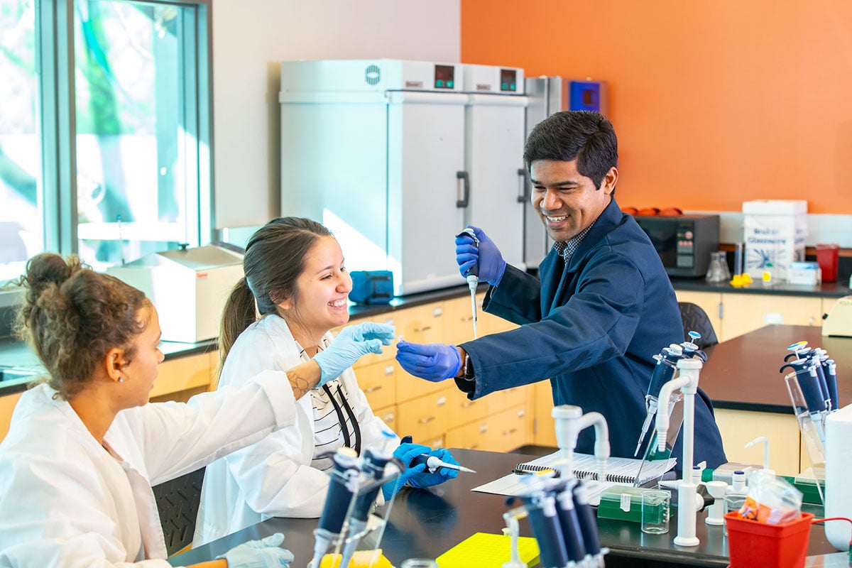 Students work with professor in chemistry lab