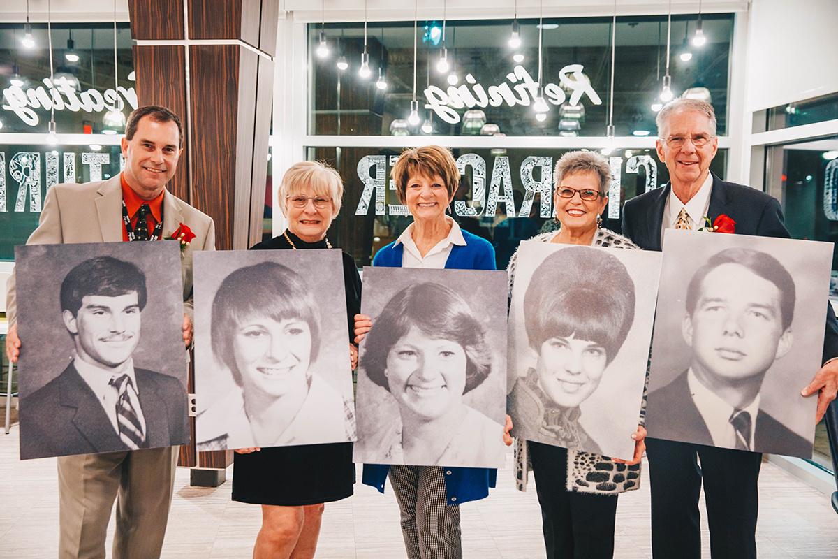 group of alumni holding photos from their college years