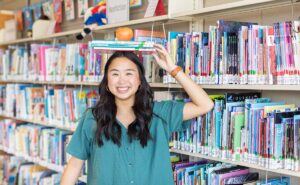 girl balancing books and apple on head