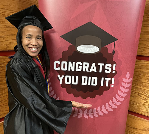 SNU Graduate, Lauren Morrison-Edwards, standing next to sign that says "Congrats, you did it!"