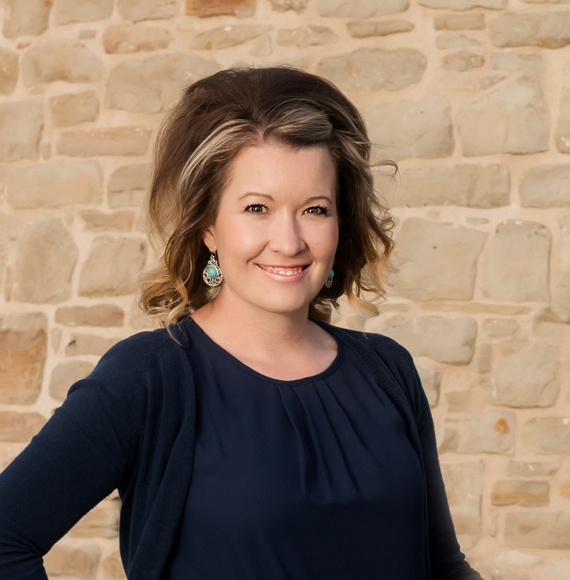 misty berg standing by a stone wall smiling